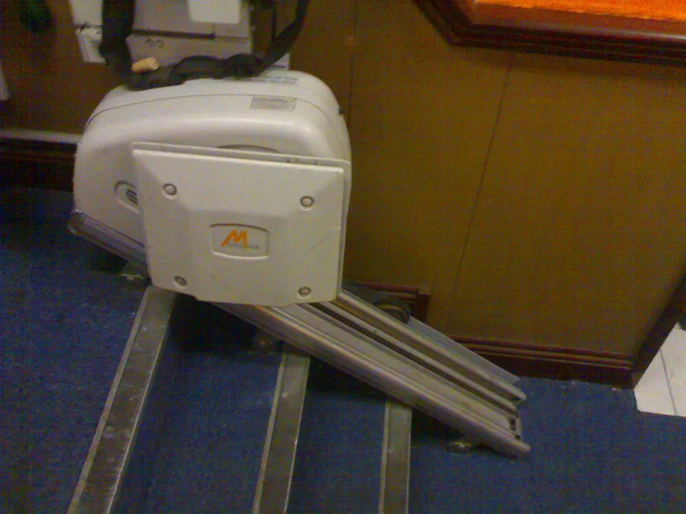 Close-up view of a stairlift seat and rail system showing the controls and seatbelt